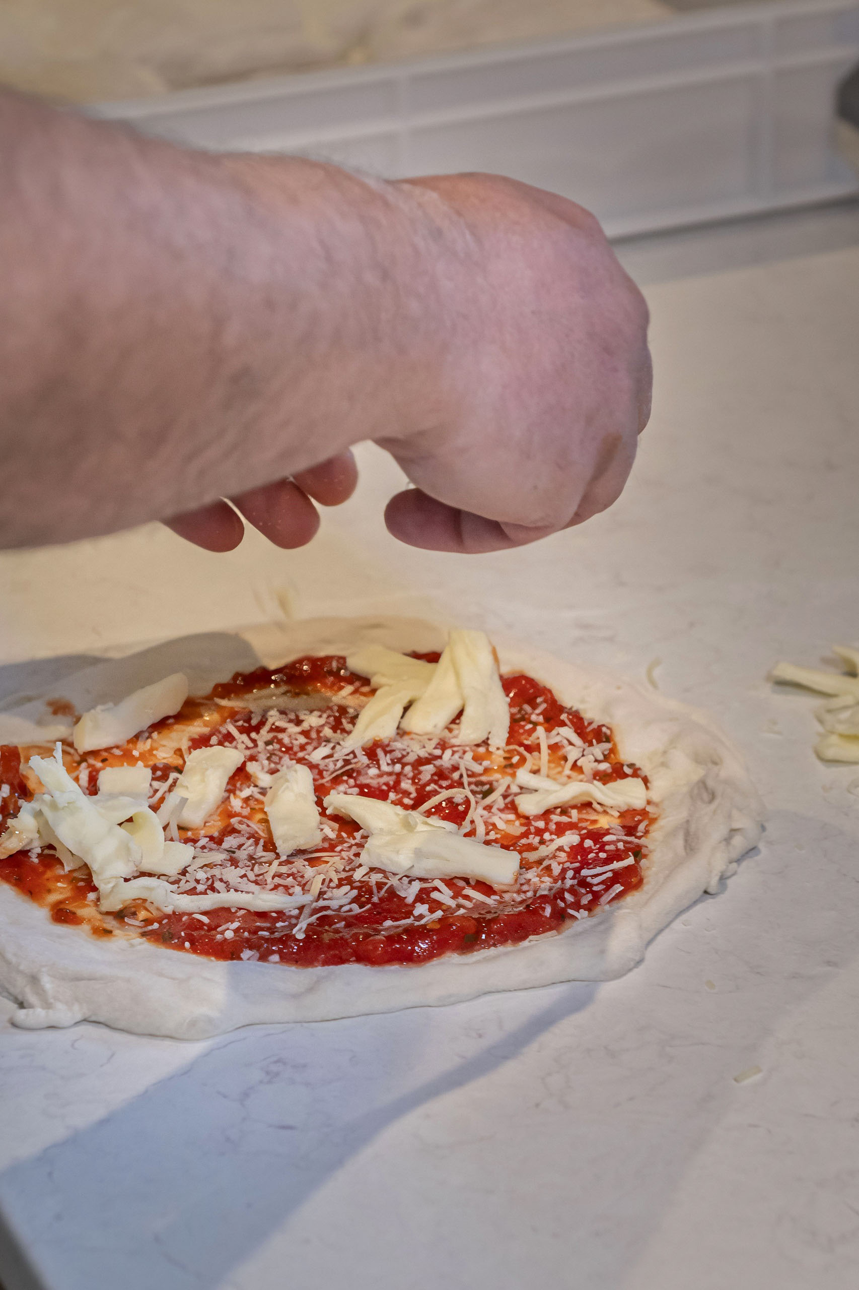 Topping a Neapolitan pizza with mozzarella and parmesan